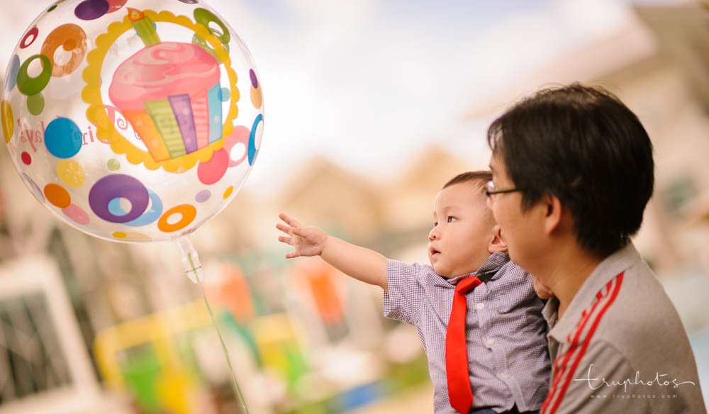 Birthday baby reaching out for balloon at first birthday party | Singapore children birthday party, baby shower photography by Truphotos