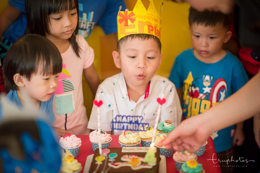 Birthday boy wearing a party hat and blowing out the candles on cake at his birthday party at McDonald's.